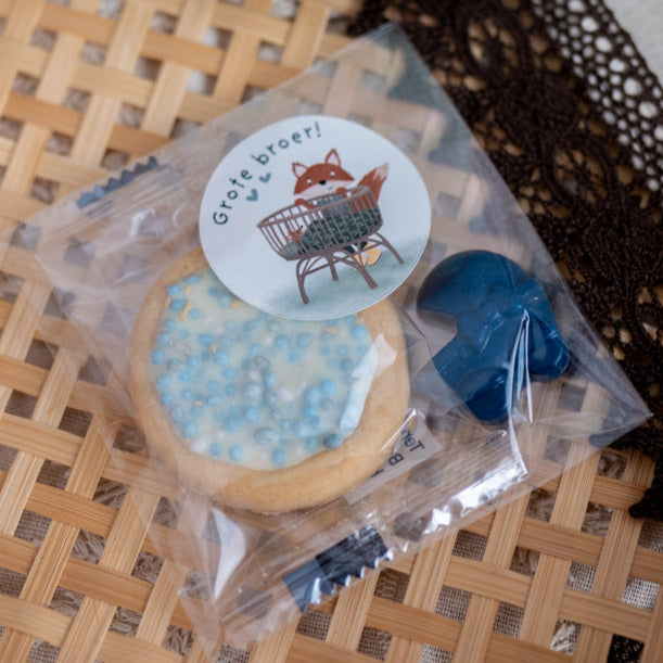 Geboorte traktatie jongen met blauw waskrijtje, blauw geboortekoekje en sticker op het zakje