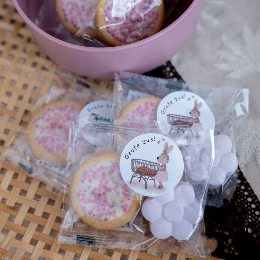 Geboorte_traktatie_meisje met roze bloem stoepkrijtje, roze geboortekoekje en een sticker op het zakje